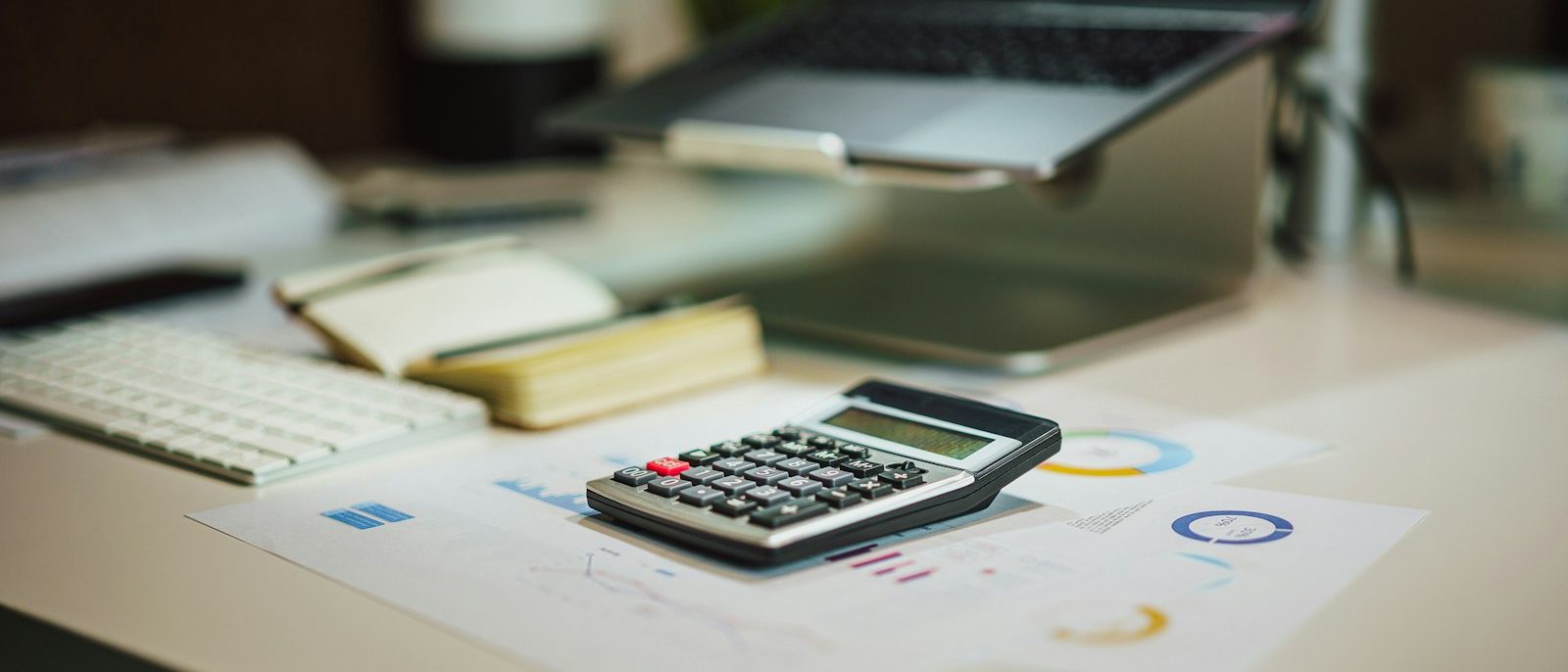 Skaičiuotuvas ant finansinių ataskaitų prie kompiuterio